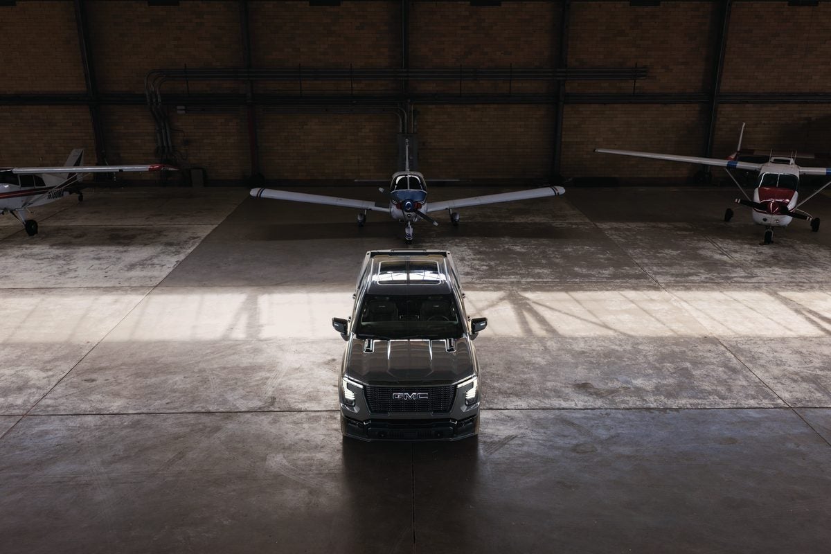 2027 GMC Sierra 1500 Denali Ultimate parked inside an aircraft hangar between small planes