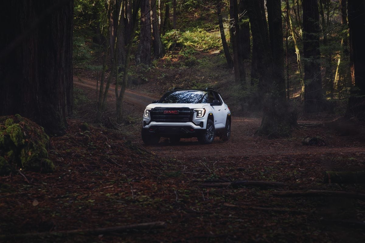 White GMC Terrain AT4 rolling down a forest dirt road between tall redwoods