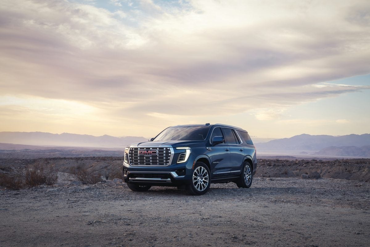 Blue GMC Yukon Denali parked on a gravel overlook under a wide evening sky