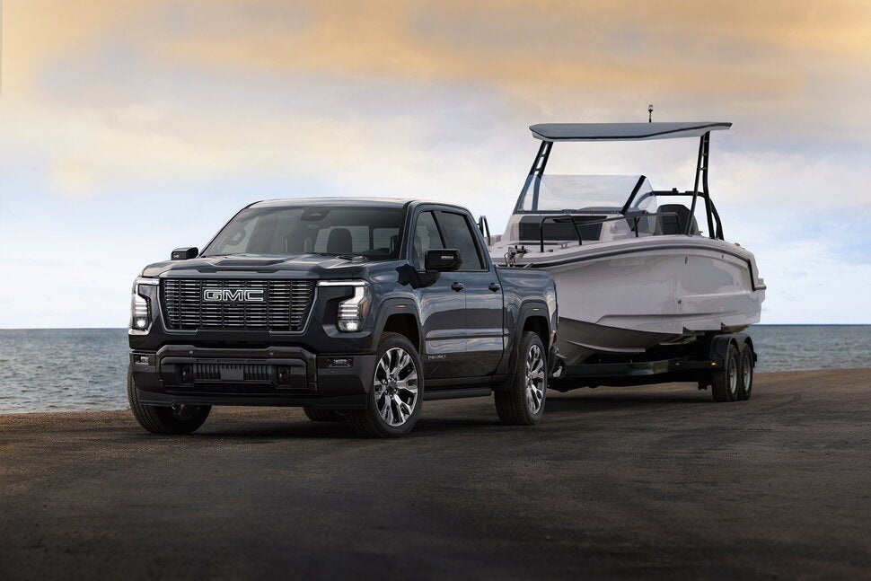 2027 GMC Sierra 1500 Denali Ultimate towing a boat at the coast