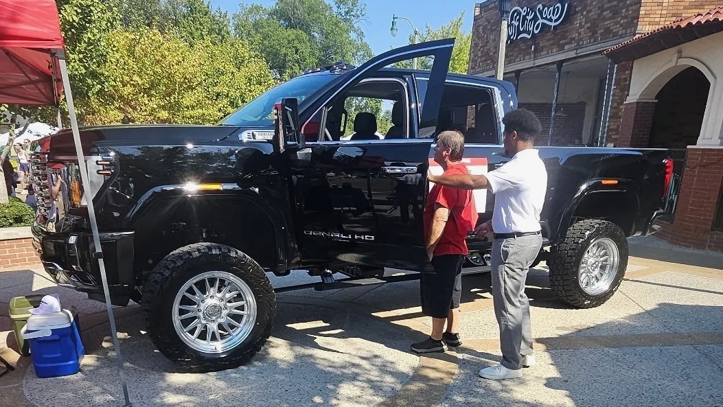 A festivalgoer looks inside the lifted 2026 GMC Sierra 2500HD Denali at the Rivard-Royall GMC booth