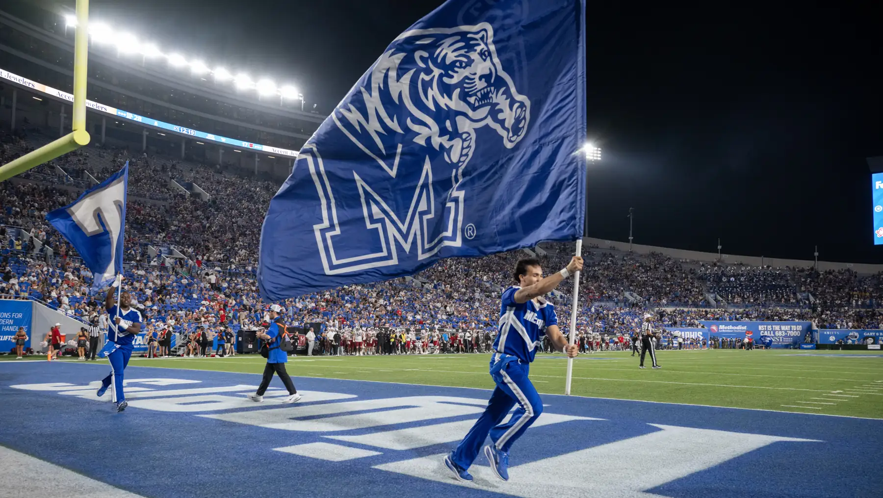 Memphis Tigers spirit squad running the tiger flag across the end zone at Simmons Bank Liberty Stadium