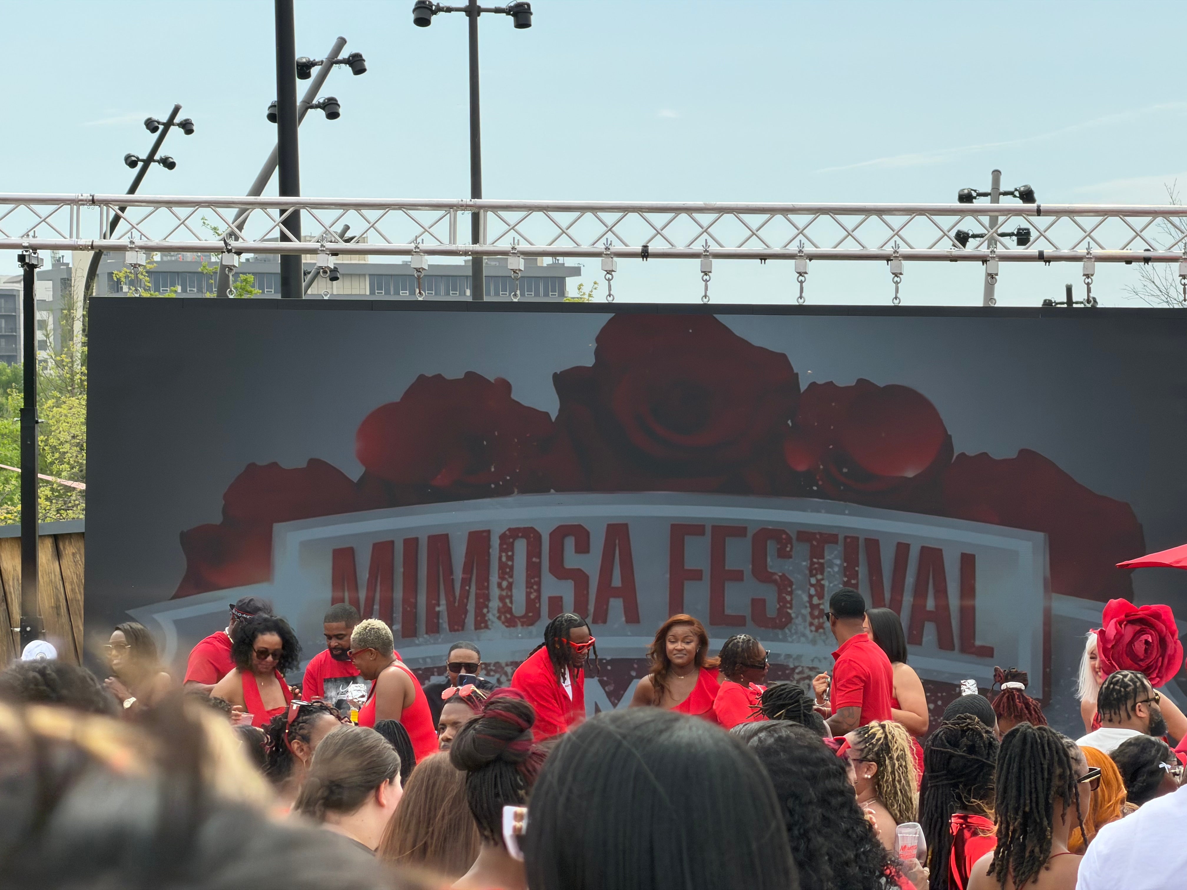 Mimosa Festival Memphis 2026 main stage banner with red roses backdrop and crowd in Downtown Memphis
